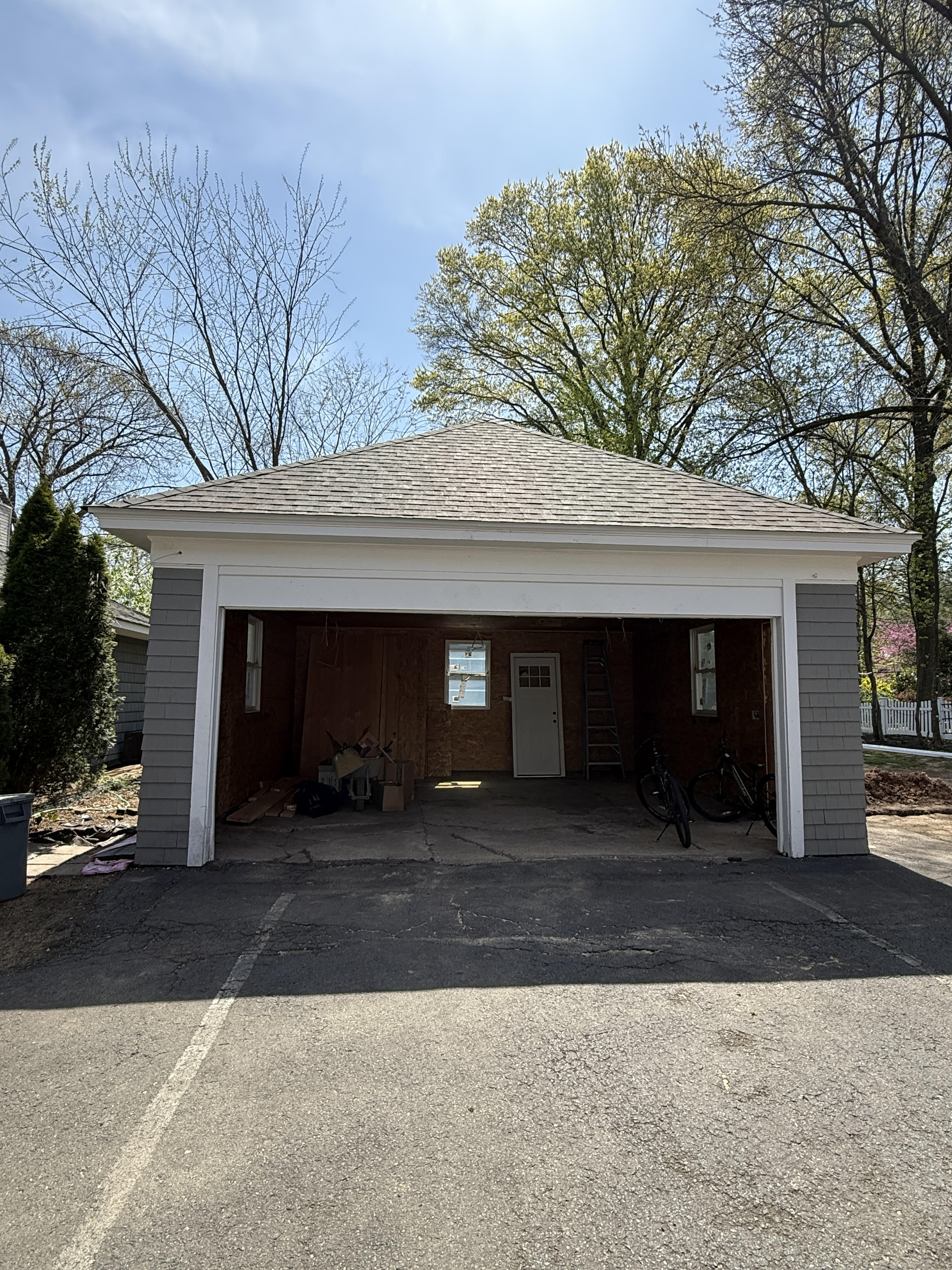 Completed garage roofing project with gray siding